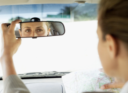 woman looking in car rear view mirror