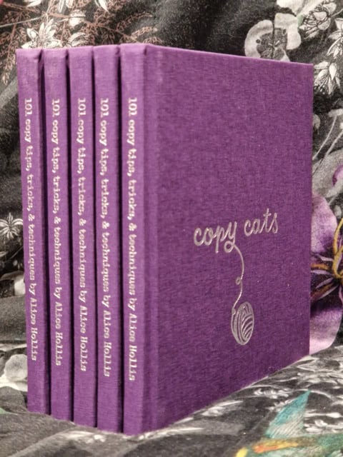5 copies of Copy Cats by Alice Hollis lined up to reveal the spines - purple book cover and silver writing